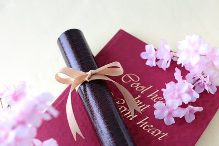 Graduation certificate, graduation album and cherry blossom petalsの写真素材