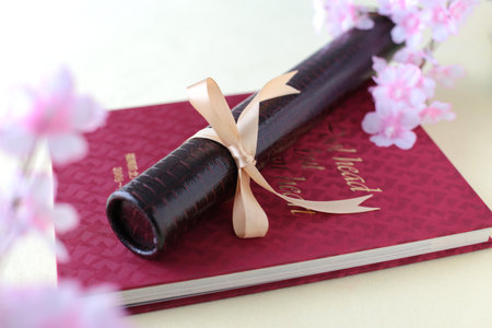 Graduation certificate, graduation album and cherry blossom petalsの写真素材