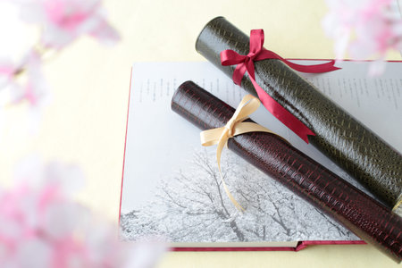 Graduation certificate, graduation album and cherry blossom petalsの写真素材