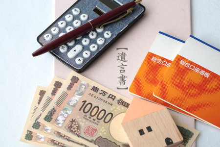 The will, the house he left behind, his bankbook, a stack of bills, a calculator, and a seal.の写真素材