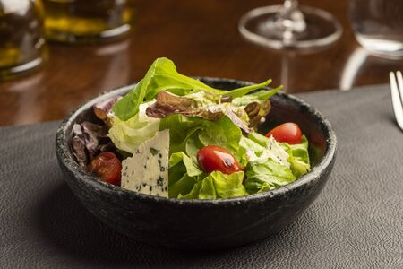 Salad with green lettuce and green leaves with blue cheese and tomatoes on a bowlの写真素材