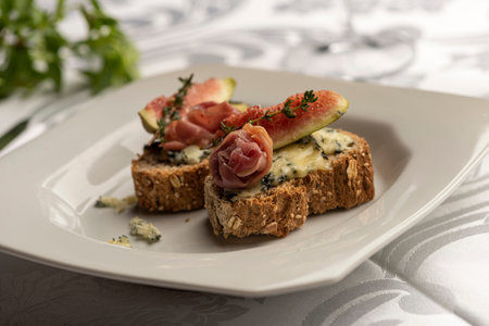 Bruschetta with blue cheese figs and parma ham on white plate on blurred background.の写真素材