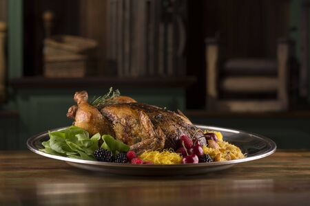 Roasted turkey chicken garnished with blackberry, red berry, cherries, and spices on a rustic table and backgroundの写真素材