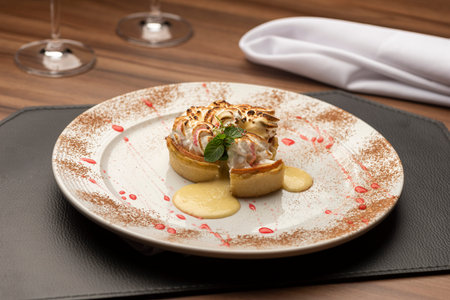 Lemon tart pie with whipped cream desert on a white decorated plate wooden table and blurred...