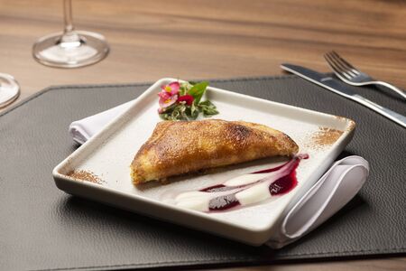 sweet strawberry and cream crepe on a white plate and leather mat and wooden tableの写真素材