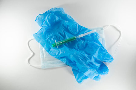 disposable blue medical mask, gloves and syringe on a white background.