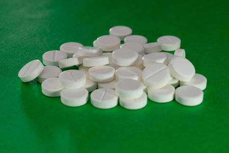 white pills scattered on a green background.