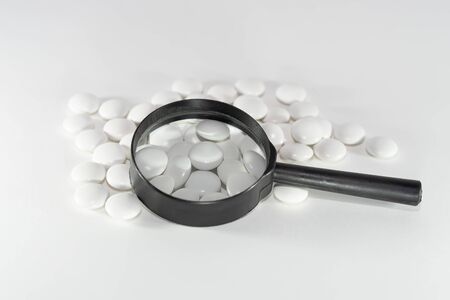 white pills through a magnifier. On white backgroundの写真素材