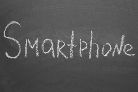 Handwritten inscription in chalk smartphone on a gray boardの写真素材