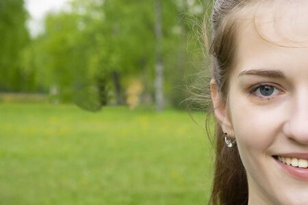 Portert girl in the park on a background of grass and trees. Half face.の写真素材