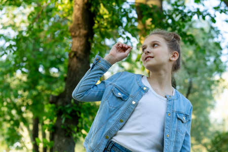 Girl in blue denim clothes posing in the park. Front viewの写真素材