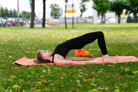 Gymnast schoolgirl warming up in a grass park before performing complex exercises. Series of photosの写真素材