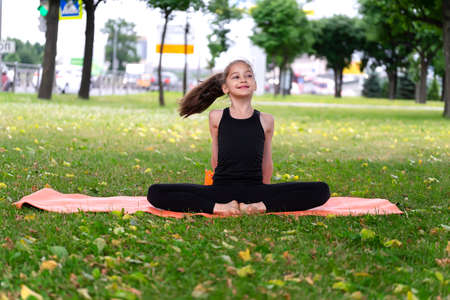 Gymnast schoolgirl warming up in a grass park before performing complex exercises. Series of photosの写真素材