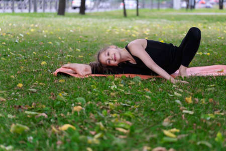 Gymnast schoolgirl warming up in a grass park before performing complex exercises. Series of photosの写真素材