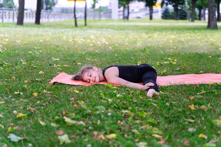 Gymnast schoolgirl warming up in a grass park before performing complex exercises. Series of photosの写真素材