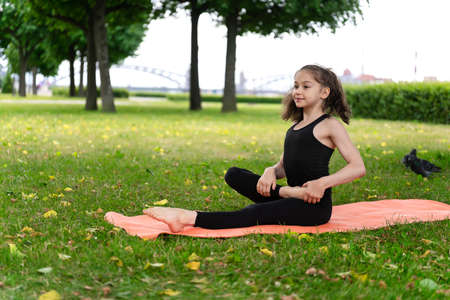 Gymnast schoolgirl warming up in a grass park before performing complex exercises. Series of photosの写真素材