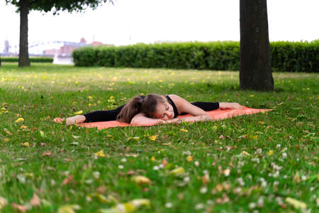 Gymnast schoolgirl warming up in a grass park before performing complex exercises. Series of photosの写真素材
