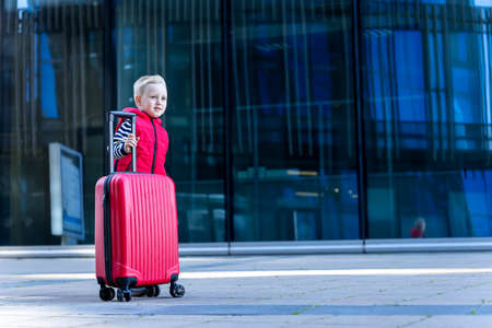 Little boy traveler on the background of modern buildings. Front viewの写真素材