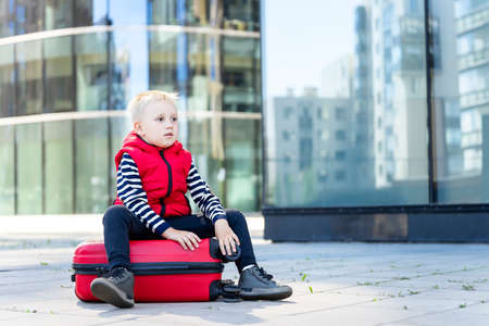 Little boy traveler on the background of modern buildings. Front viewの写真素材