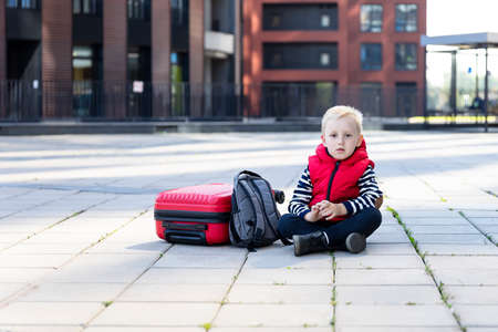 Little boy traveler on the background of modern buildings. Front viewの写真素材