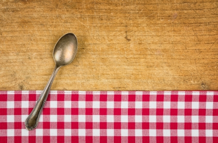 Silver spoon on a wooden board with a checkered tableclothの写真素材