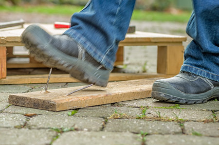 Worker with safety boots steps on a nail