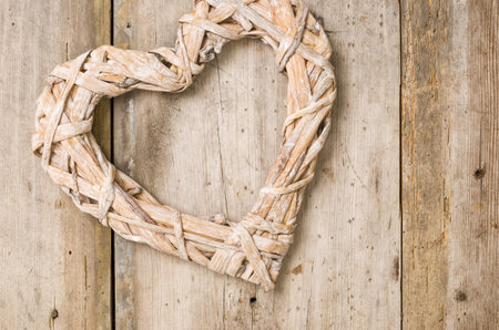 Braided heart in front of a rustic wooden backgroundの写真素材
