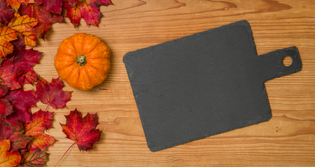 Autumn foliage with a pumpkin and an empty blackboardの写真素材
