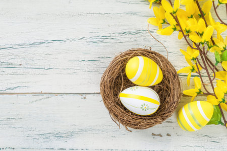 An easter nest with yellow easter eggs on a wooden background