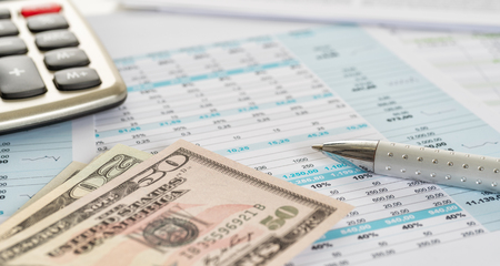 Dollar bills on documents with a calculatorの写真素材