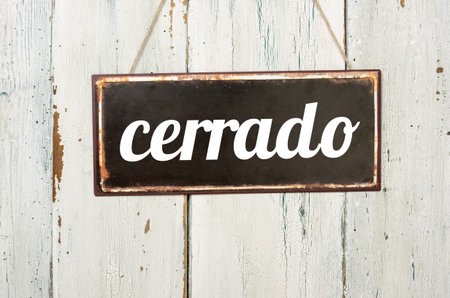 Vintage tin sign on a wooden background - Closed in spanishの写真素材