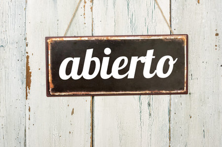 Vintage tin sign on a wooden background - Open in spanishの写真素材