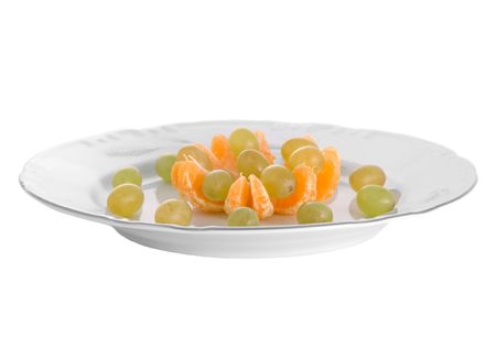 Peeled tangerines and grapes on plate isolated on whiteの写真素材