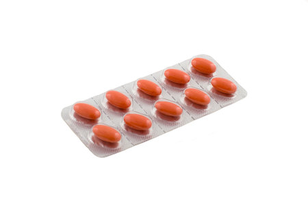 Single blister filled with orange pills isolated on white
