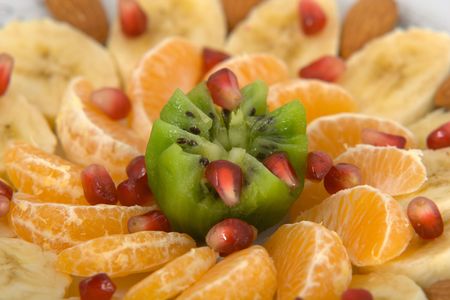Delicious fruit salad made of kiwi, tangerines, bananas, almonds and pomegranate macroの写真素材