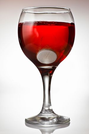 Medicine and alcohol - Fizzy tablet in a goblet of red wineの写真素材