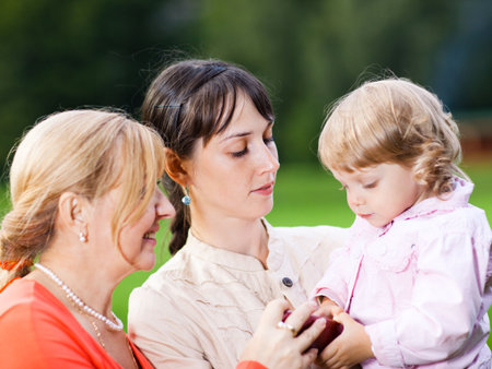 Three generation family in a park - shallow DOF, focus on a central person's face