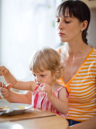 Little girl with her mom having a dinner - shallow DOFの写真素材