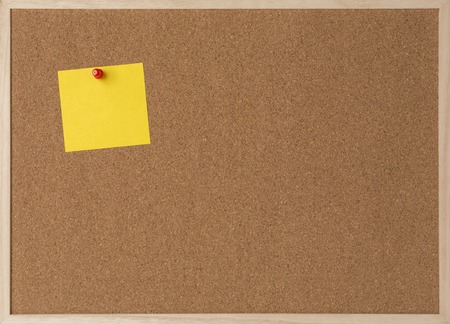 Sticky yellow note on wooden frame cork board.の写真素材