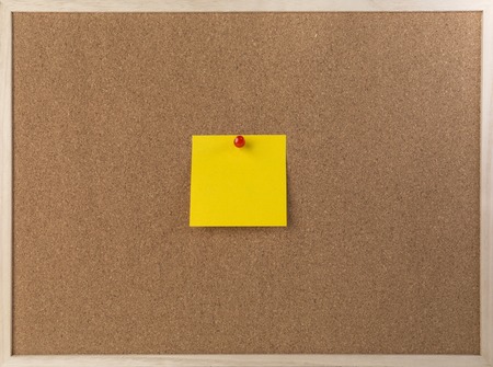 Sticky yellow note on wooden frame cork board.の写真素材