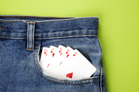 Playing cards in blue jeans pocket with green background