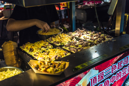 Taipei, Taiwan - June 21, 2018: A Taiwanese stall vendor busying making the Japanese snack food called Takoyaki at the Raohe night market.のeditorial素材