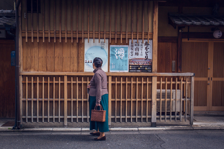 Kyoto, Japan - November 19, 2018: A senior Japanese woman looking at a poster outside of a theater house.のeditorial素材