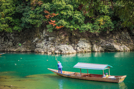 Kyoto, Japan - November 23, 2018: Boatman punting the boat for tourists to enjoy the autumn view along the bank of Hozu river in Arashiyama Kyoto, Japanのeditorial素材