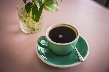 Coffee with beautiful latte art in green cup and saucer on wooden table in a cafe