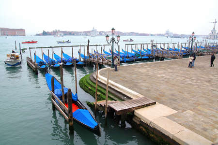 Black wooden gondolas lining up along the shore, Veniceの写真素材