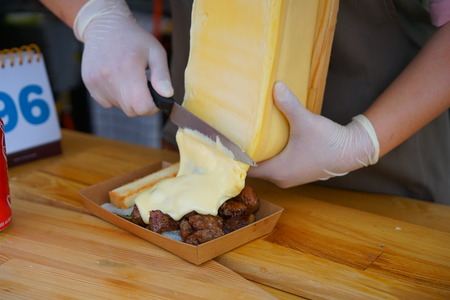 Cut the melted cheese with a knifeの写真素材