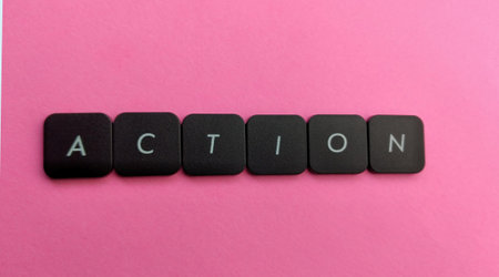 Action word made with black plastic buttons on pink background. Business concept