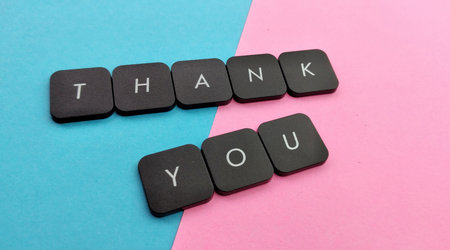 Thank you text on black plastic buttons on pink and blue background.の写真素材