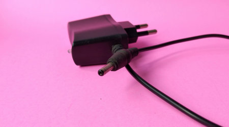 Charger plug on pink background. Power supply for mobile phone.